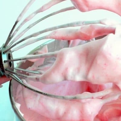 Whipping attachment lifting out strawberry mousse out of a bowl.