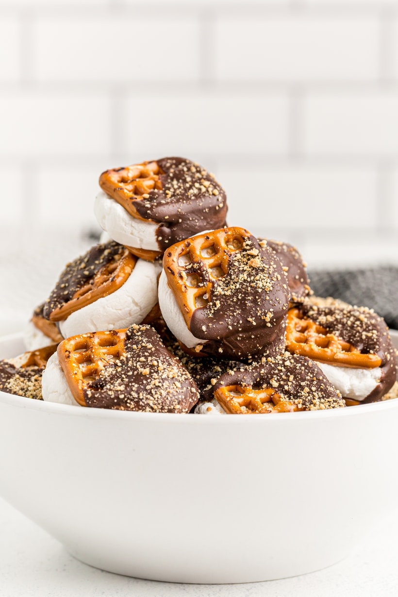 Bowl of stacked s’mores pretzels coated in chocolate and sprinkled with crushed graham crackers