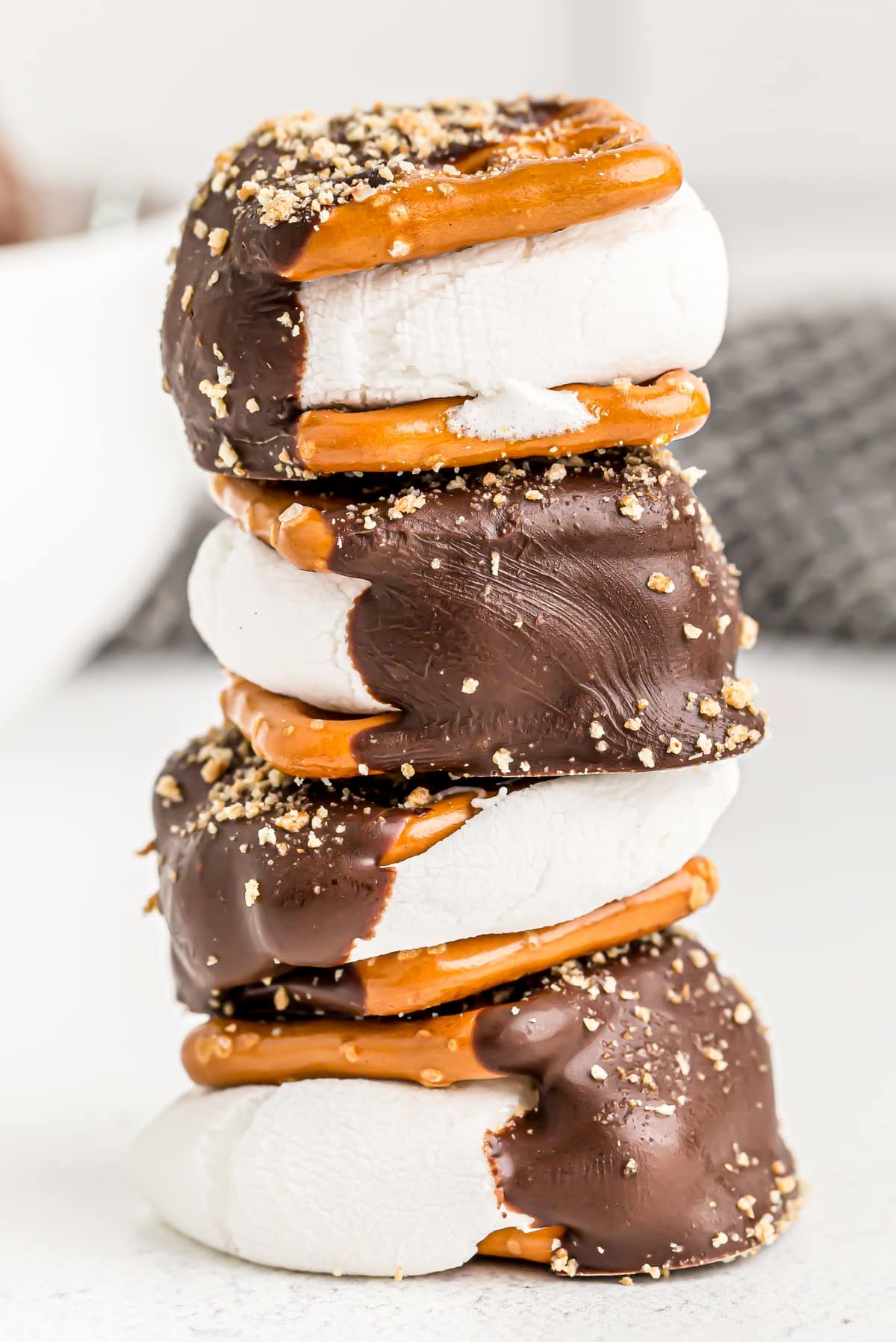 Stack of four gooey s’mores pretzels showing marshmallow layers and chocolate-dipped sides