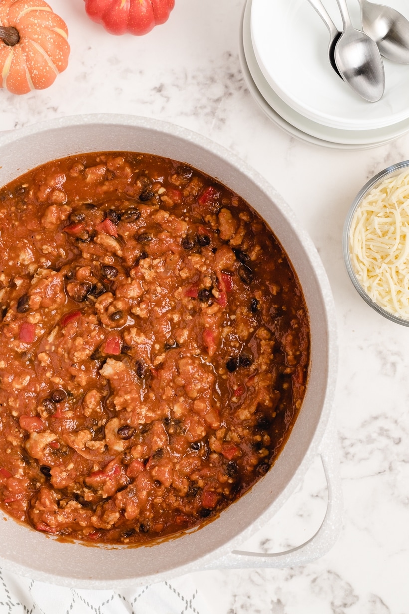 Dutch oven filled with savory pumpkin chili simmered with turkey, beans, and peppers.