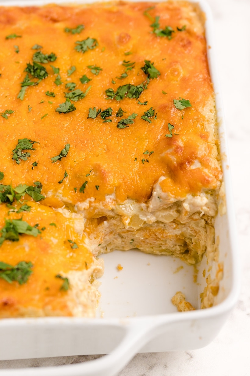 Green Chile Chicken Enchilada Casserole with one piece missing Top view of Green Chile Chicken Enchilada Casserole with a slice removed