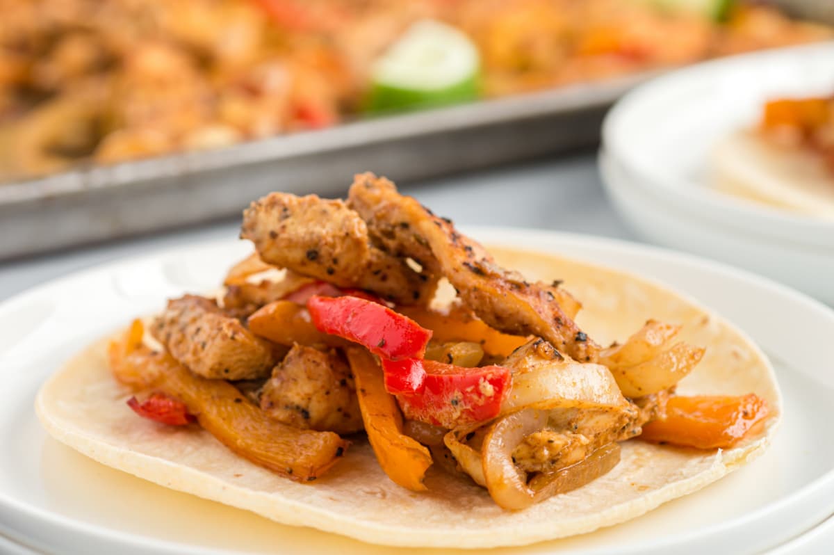 A serving of Sheet Pan Chicken Fajitas A plated serving of baked chicken fajitas with peppers and onions, shown from the side.