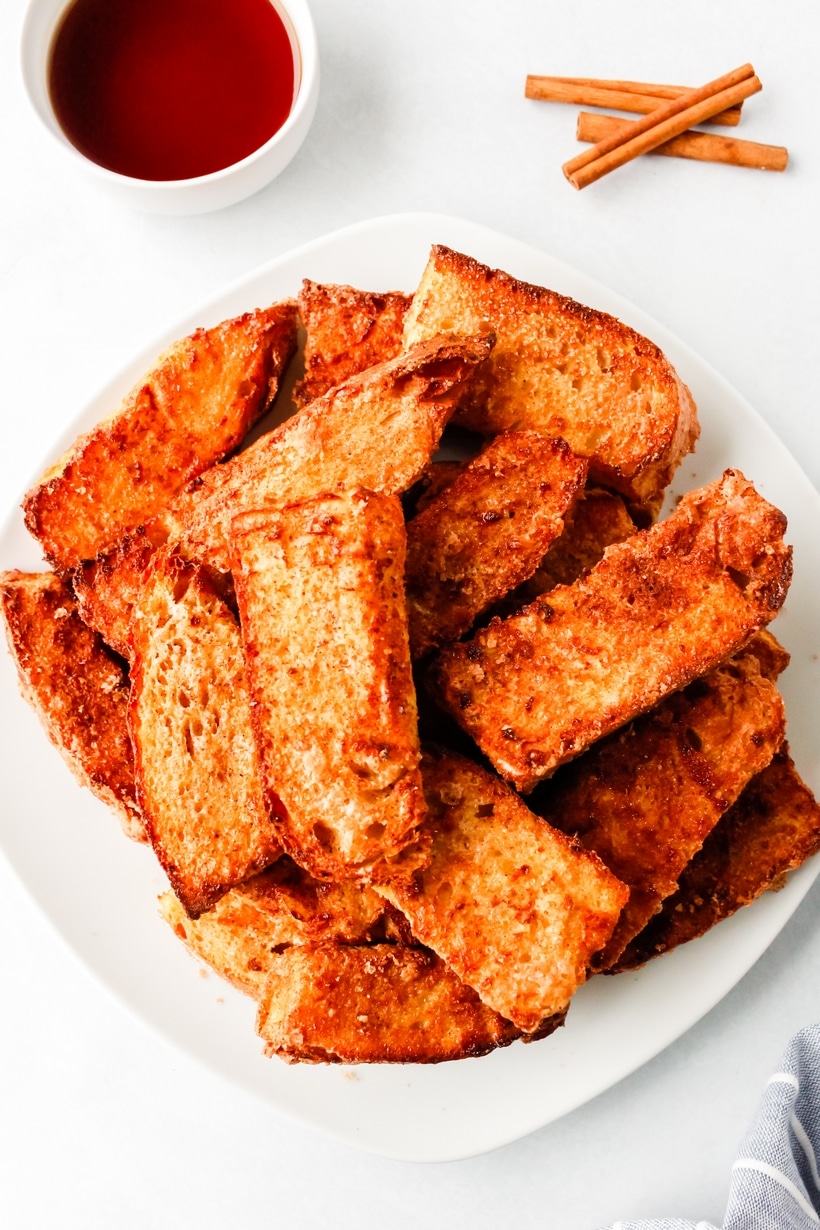 Air Fryer French Toast piled on a plate french toast on a white plate that has been air fried