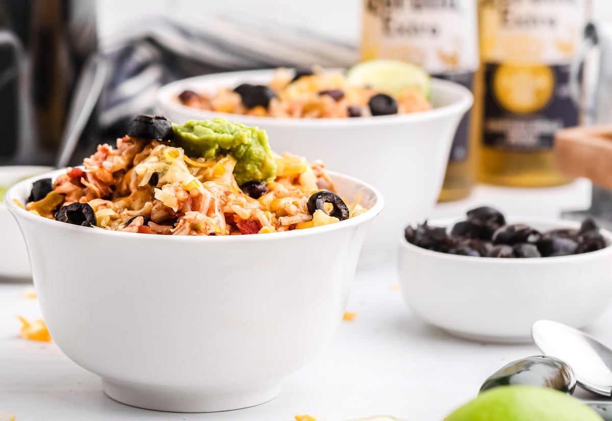Slow Cooker Chicken Burrito Bowls - ten minutes of prep work rewards you later with a delicious and hearty dinner. Just dish yourself a bowl and garnish to your liking. slow cooker chicken burrito Bowls side view with instant rice and avocado