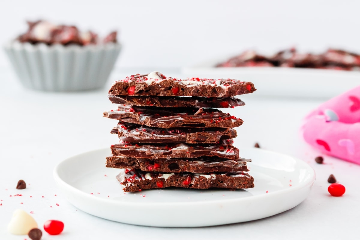 Valentine's Day Chocolate Bark on a plate A plate of chocolate bark pieces, arranged to showcase the layers and festive red candy topping.