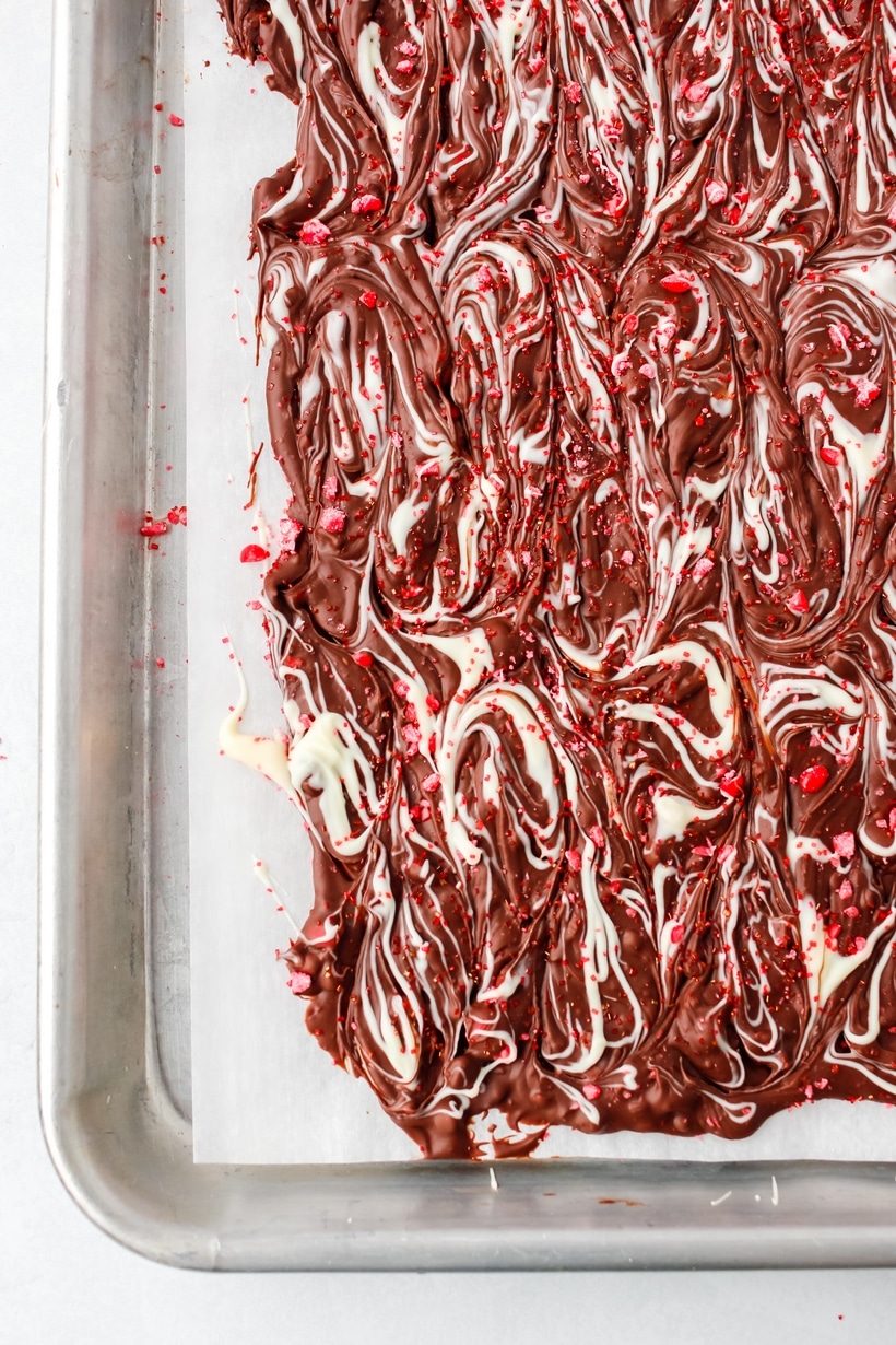 Valentine's Day chocolate bark on a cookie sheet A batch of freshly made Valentine's Day chocolate bark on a parchment-lined cookie sheet, ready to be broken into pieces.