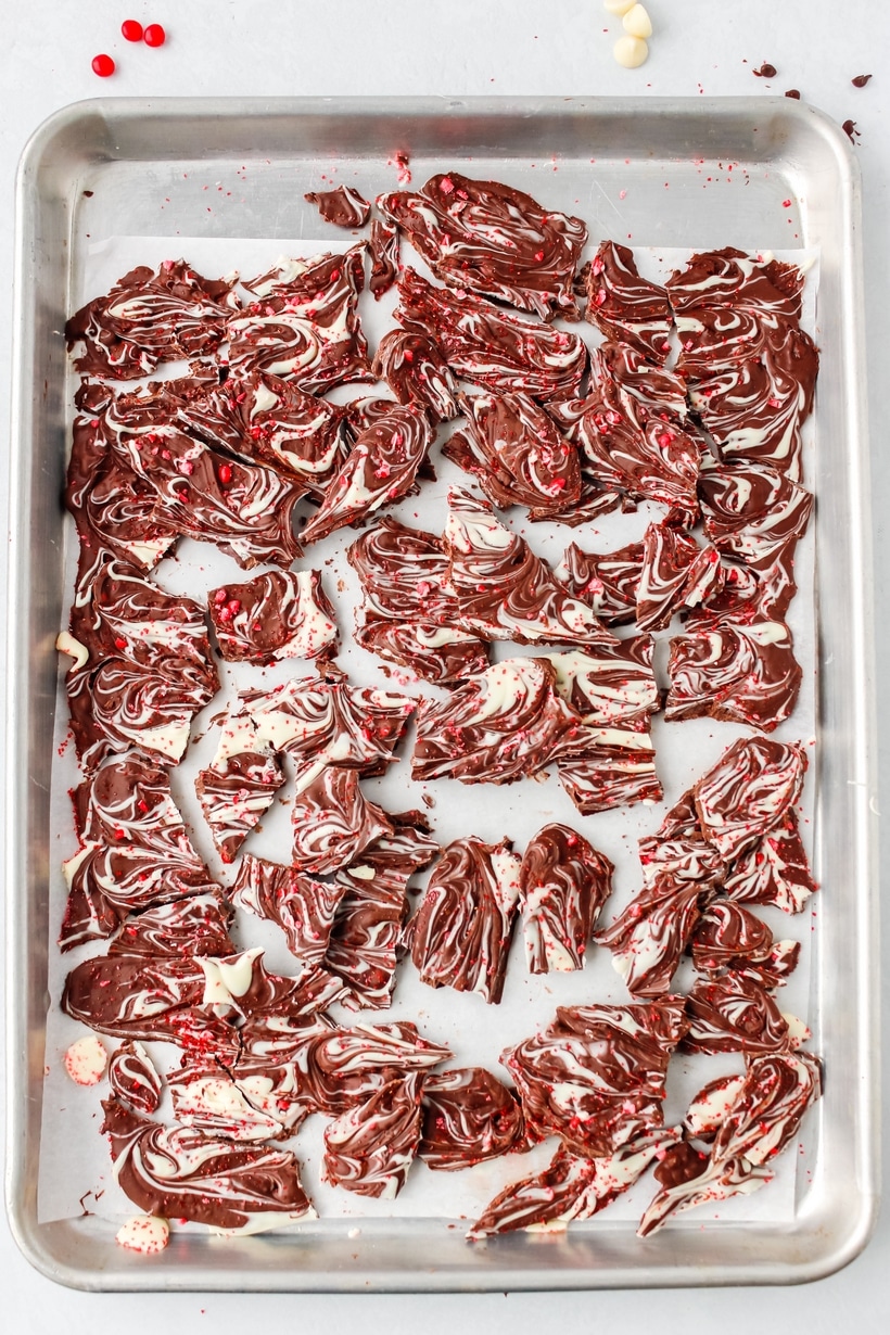 Valentine's Day Chocolate Bark broken into pieces. A close-up of a piece of chocolate bark, showing the marbled white and dark chocolate with bits of cinnamon candy.