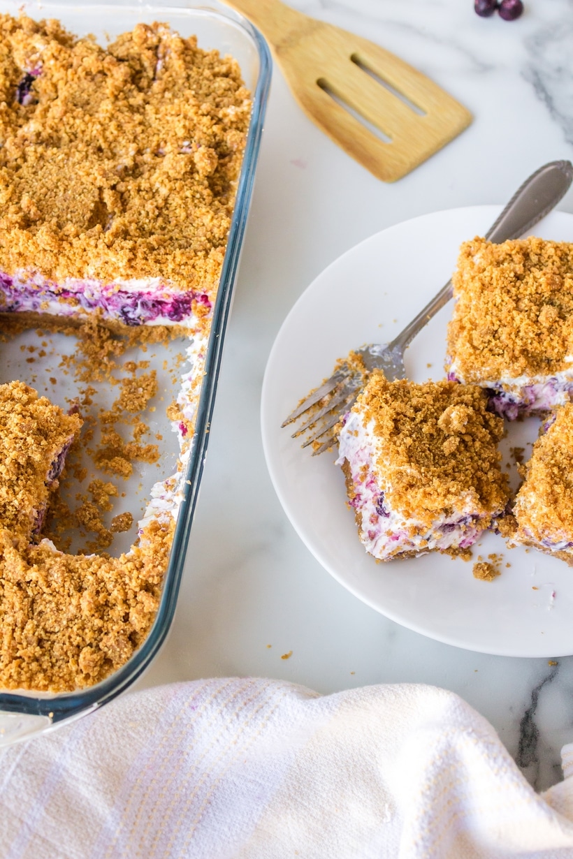 Blueberry Cheesecake Icebox Cake with slices served Overhead shot of blueberry cheesecake icebox cake with three slices on a plate