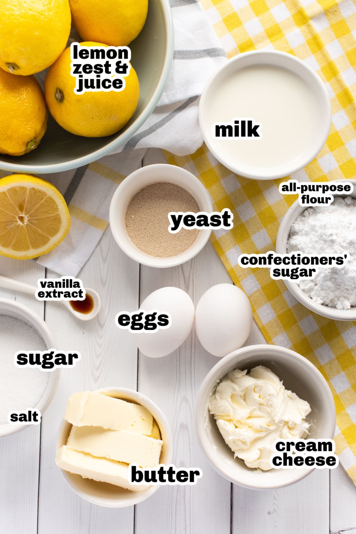 Lemon Buns with Lemon Cream Cheese Icing ingredients A flat lay of ingredients for lemon buns, including flour, sugar, butter, eggs, milk, yeast, and fresh lemons.