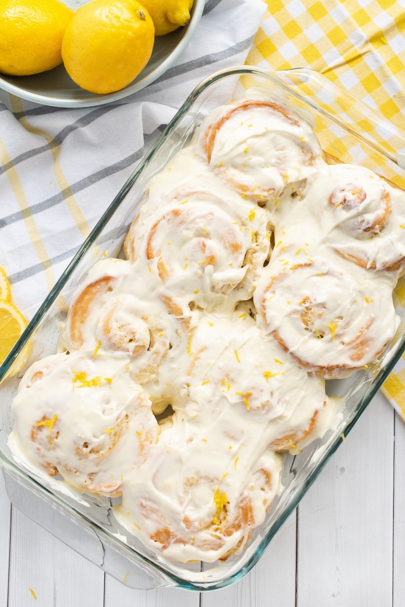 Lemon Buns with Lemon Cream Cheese Icing are a delicious alternative to the classic cinnamon roll. A close-up top view of warm lemon buns in a baking dish, covered in smooth cream cheese icing.