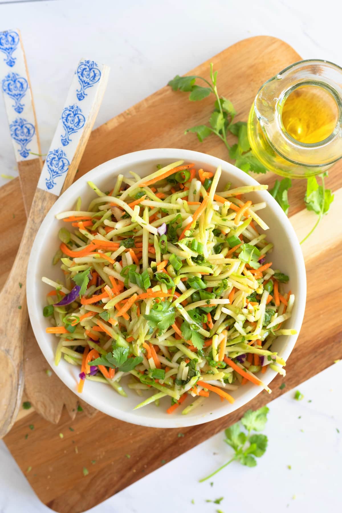 Cilantro Lime Broccoli Slaw on a cutting board. Cilantro lime broccoli slaw served in a bowl, topped with green onions and ready to enjoy.