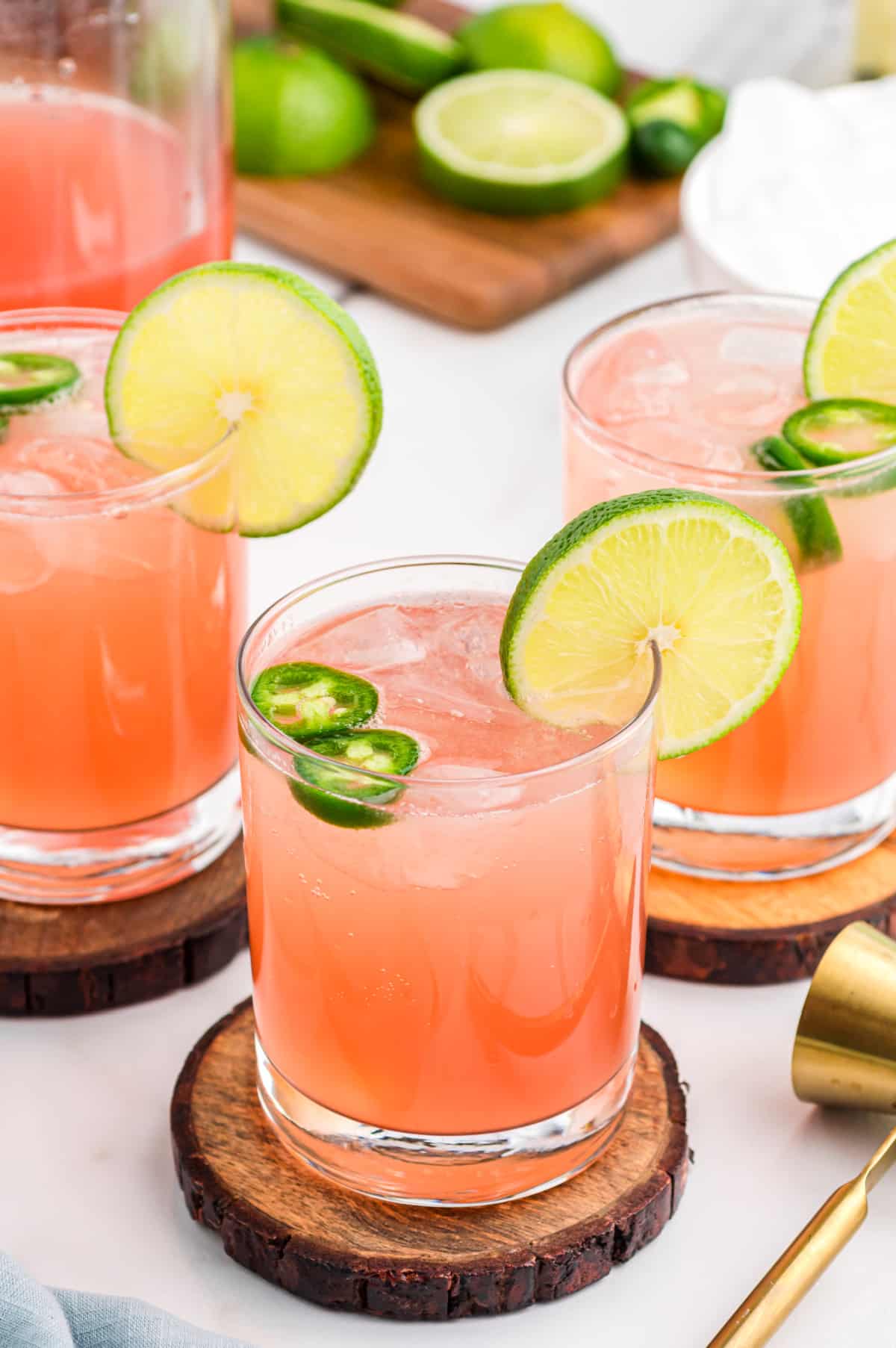 Three finished glasses of spicy watermelon jalapeño margarita garnished with lime and jalapeño