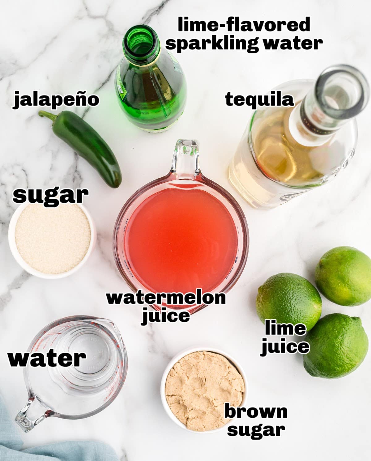 Overhead of ingredients for spicy watermelon margarita including juice, sugars, jalapeño, lime, and tequila