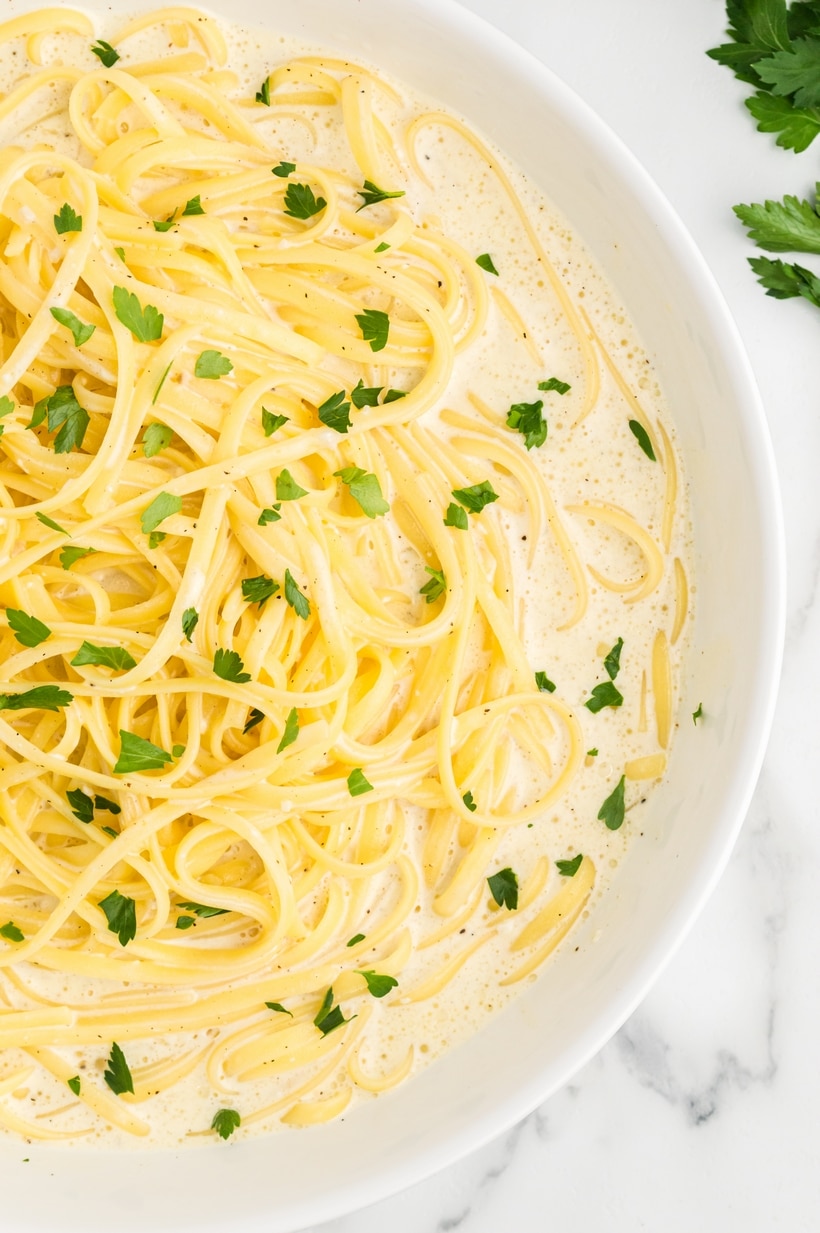 Fettuccine alfredo served in a white bowl. Overhead view of a bowl filled with fettuccine alfredo.