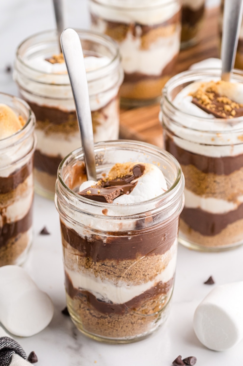 Close-up of a no-bake s’mores parfait in a jar with visible layers of graham cracker, chocolate pudding, and marshmallow topping