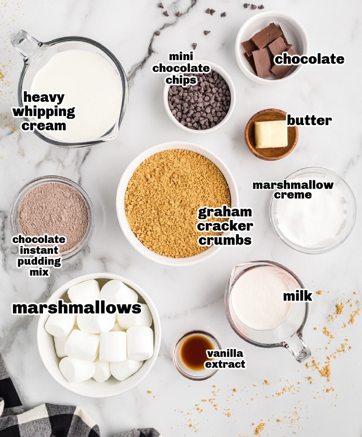 Overhead of s’mores parfait ingredients including pudding mix, graham crumbs, chocolate chips, and marshmallows