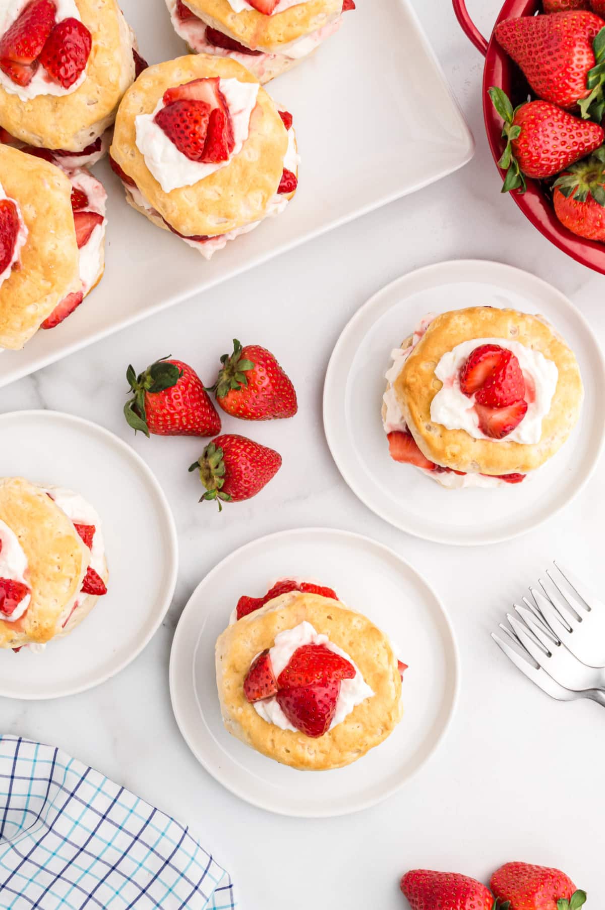 easy strawberry shortcake served on plates with whipped cream and fresh strawberries