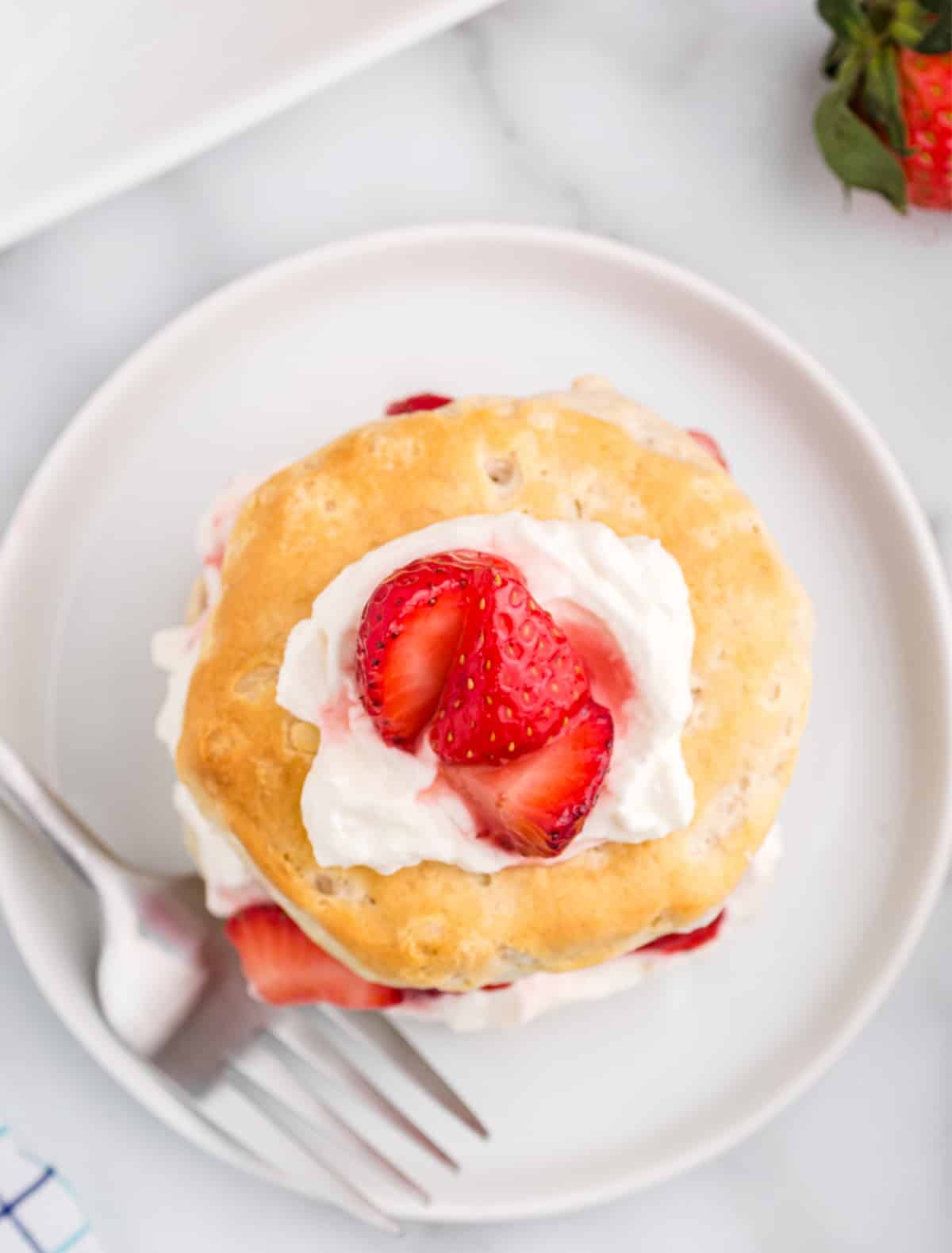 strawberry shortcake with whipped cream and fresh strawberries on a plate