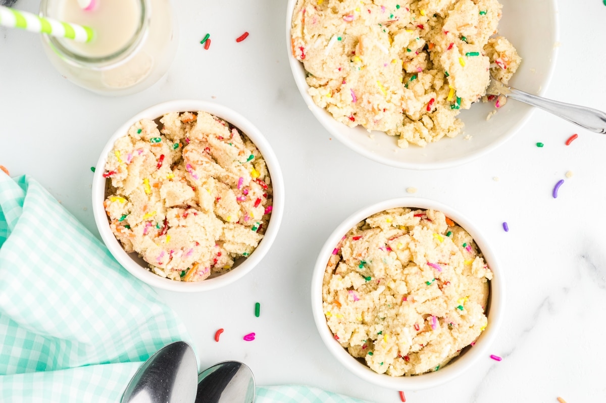 Edible Sugar Cookie Dough bowls Three small dishes of edible cookie dough topped with colorful rainbow sprinkles.