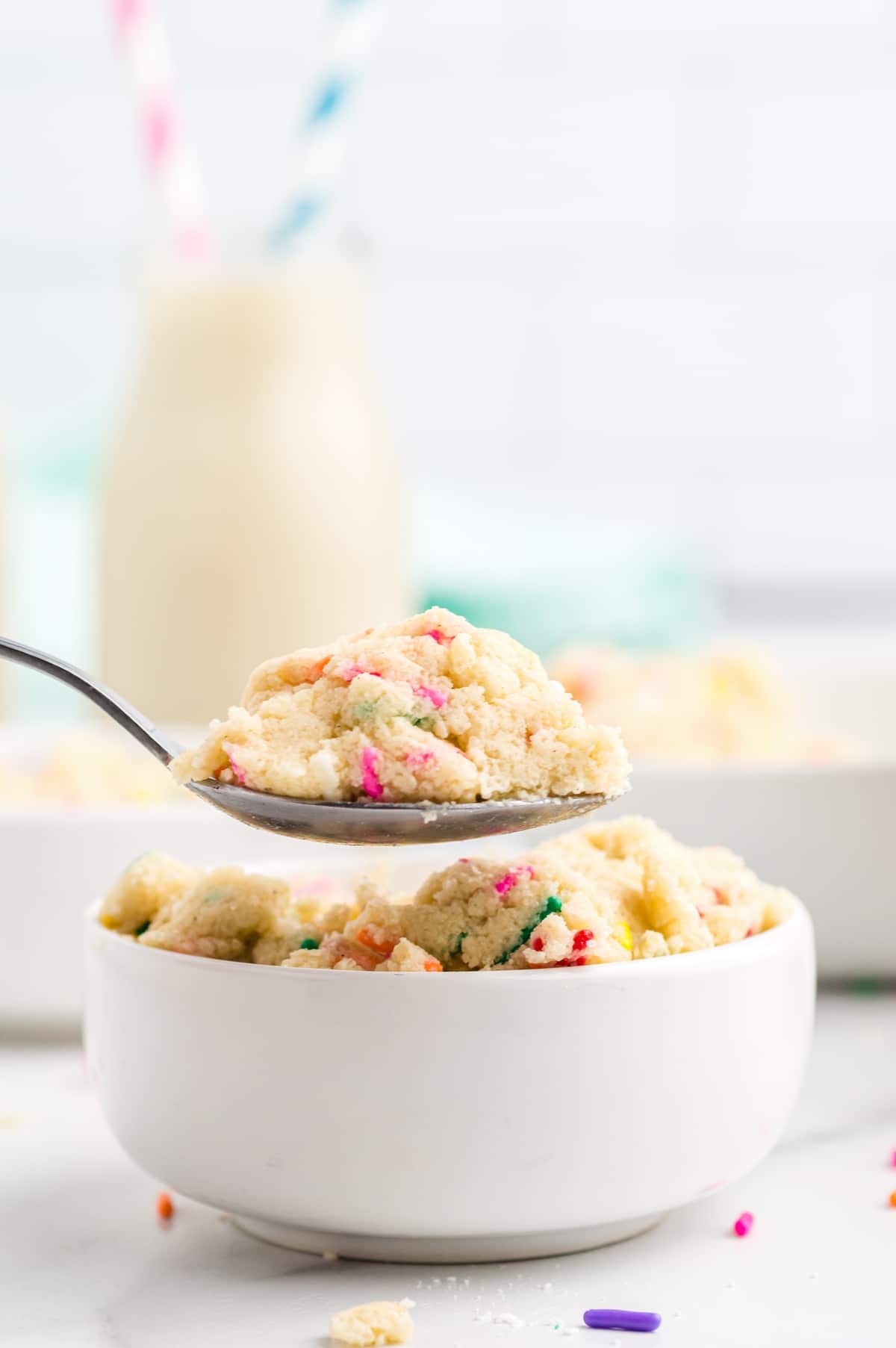 Edible Sugar Cookie Dough being spooned A small jar filled with edible sugar cookie dough, showing its smooth texture and colorful sprinkles on top.
