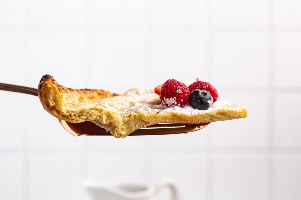 A slice of Dutch baby pancake lifted with a spatula 