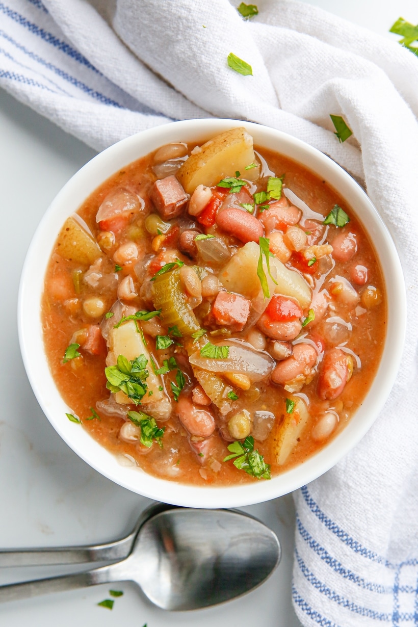 Top-down view of a bowl filled with ham and bean soup, showcasing the beans, ham, and vegetables.