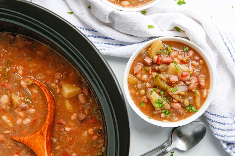 Overhead shot of a bowl of soup with the slow cooker partially visible beside it.