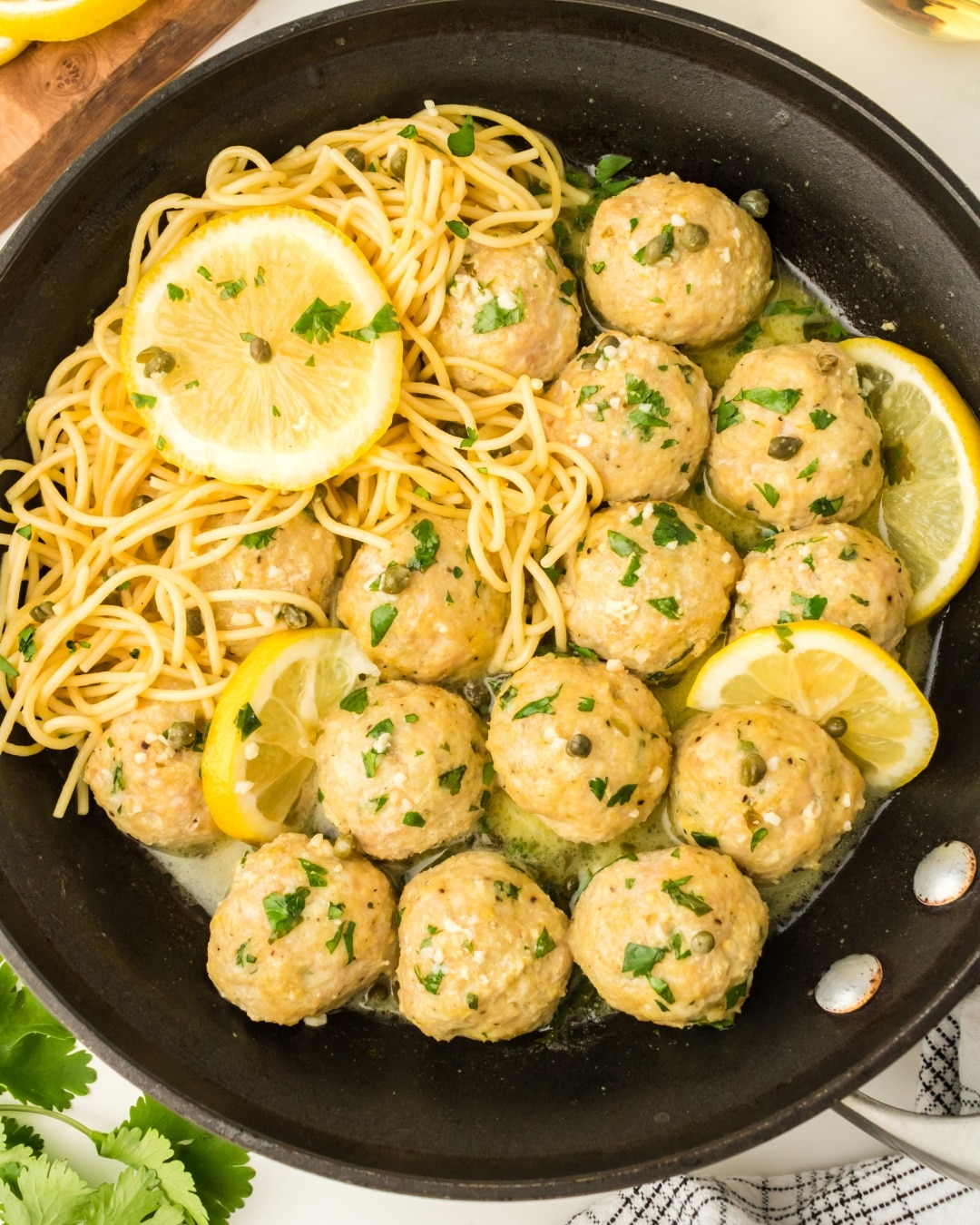 Tender Chicken Piccata Meatballs in a tangy lemon-butter sauce with capers. Pan of Chicken Piccata Meatballs drizzled with lemon-butter sauce and garnished with capers and fresh parsley.