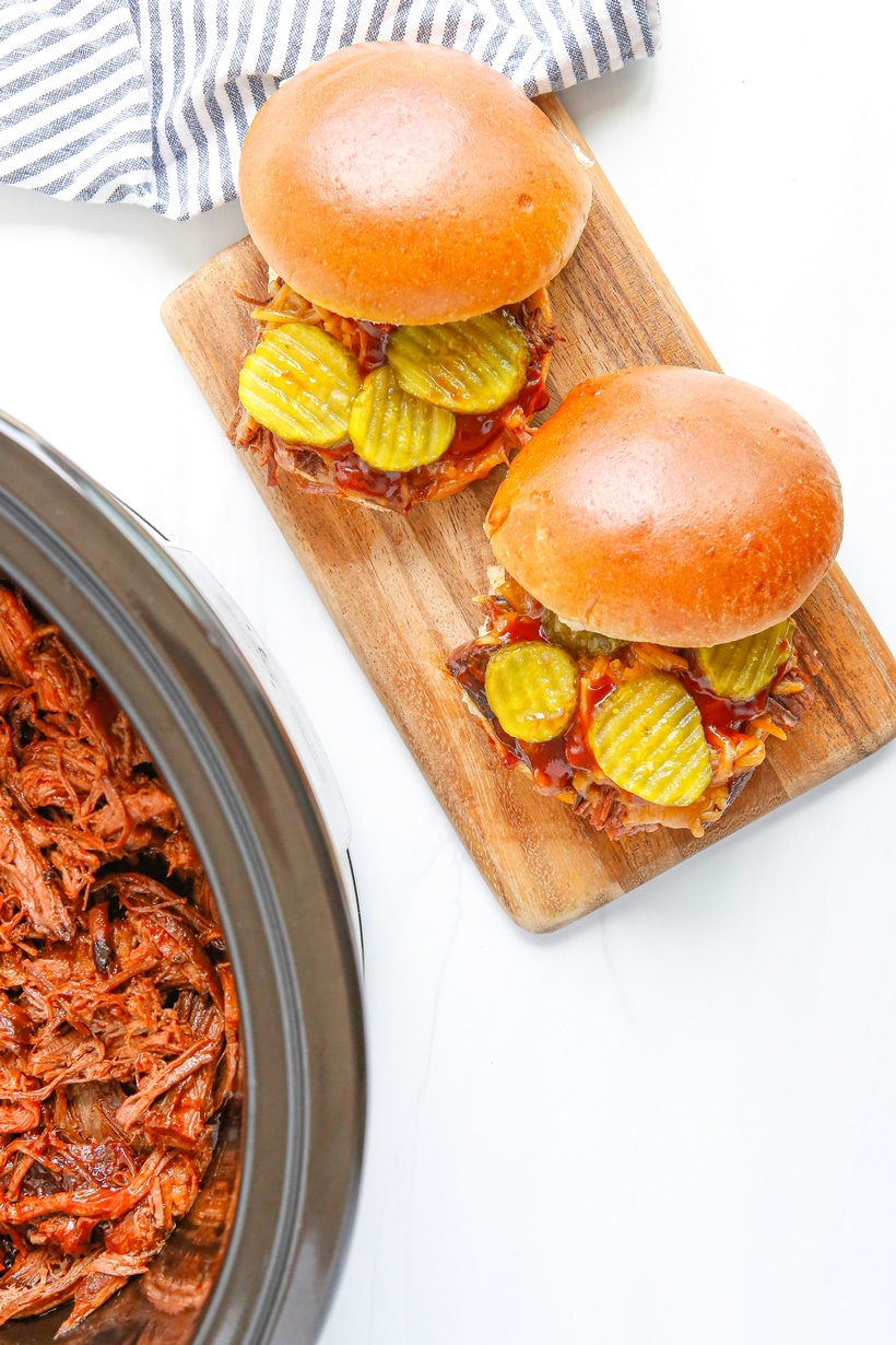 slow cooked shredded bbq beef on hamburger buns with pickles