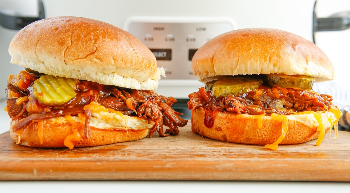 two slow cooker bbq beef sanwiches on a cutting board