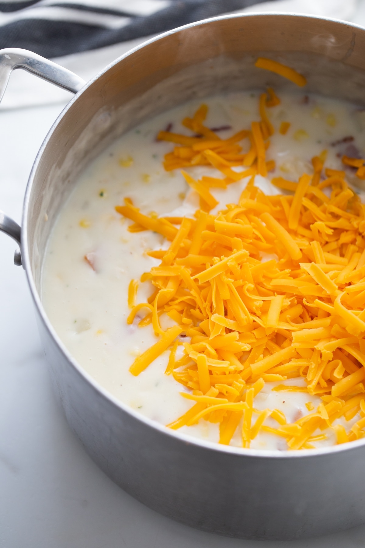 Corn chowder in pot topped with shredded cheese Chowder in a pot topped with shredded cheese, ready to melt