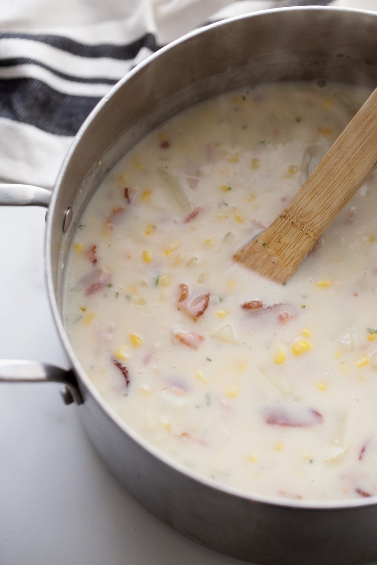 Stirring chowder in a pot for creamy texture Creamy chowder in a pot, stirred with a wooden spoon