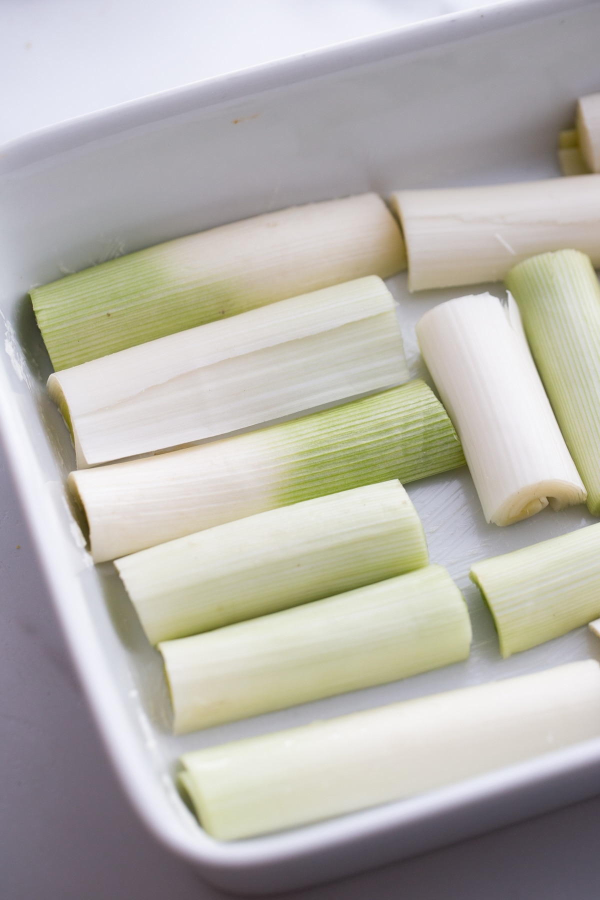 Creamy Roasted Leeks before cooking. Sliced links in a baking dish before roasting