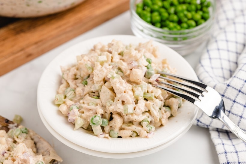 Individual serving of creamy cauliflower salad Small serving bowl of cauliflower salad with a fork beside it