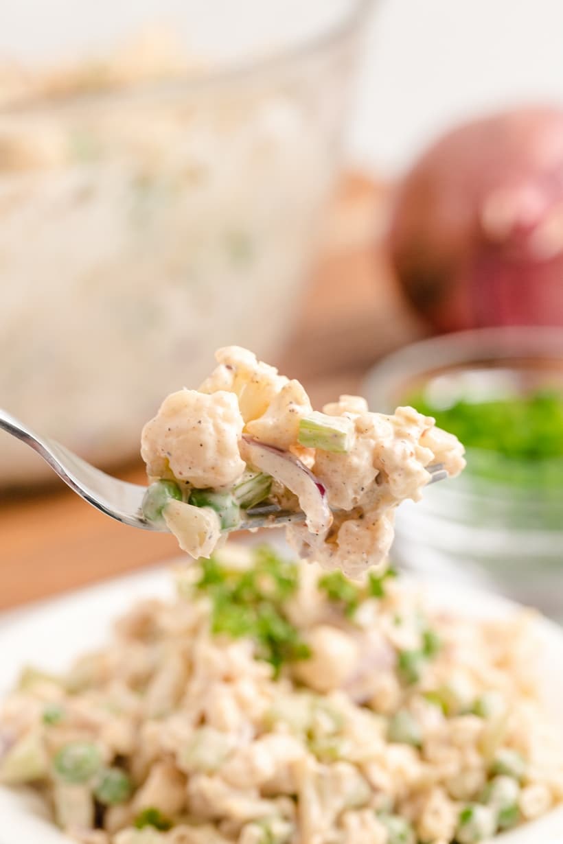 Bite of cauliflower salad on a fork Closeup of fork holding a bite of creamy cauliflower salad