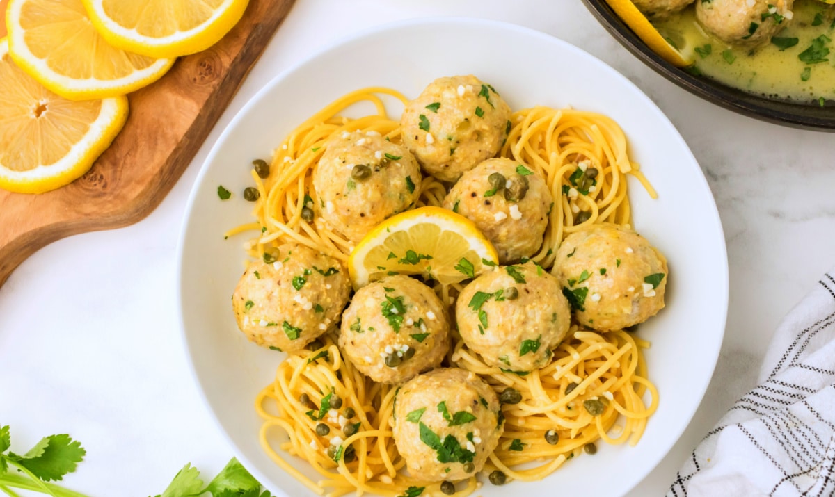 Overhead shot of chicken piccata meatballs plated with pasta and caper sauce