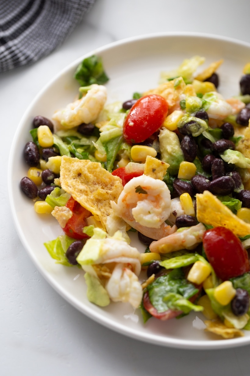 Shrimp and avocado salad packed with all your favorite ingredients and tossed with a simple homemade dressing. This salad is bright, flavorful, zesty and can definitely masquerade as seafood taco salad. It is the weeknight meal you are going to make all summer long. A healthy, Tex-Mex inspired shrimp and avocado taco salad with a zesty dressing and crispy tortilla chips on top.