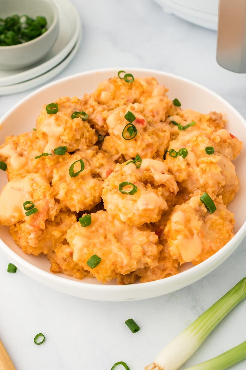 Bowl of air fried shrimp coated in bang bang sauce, ready to serve