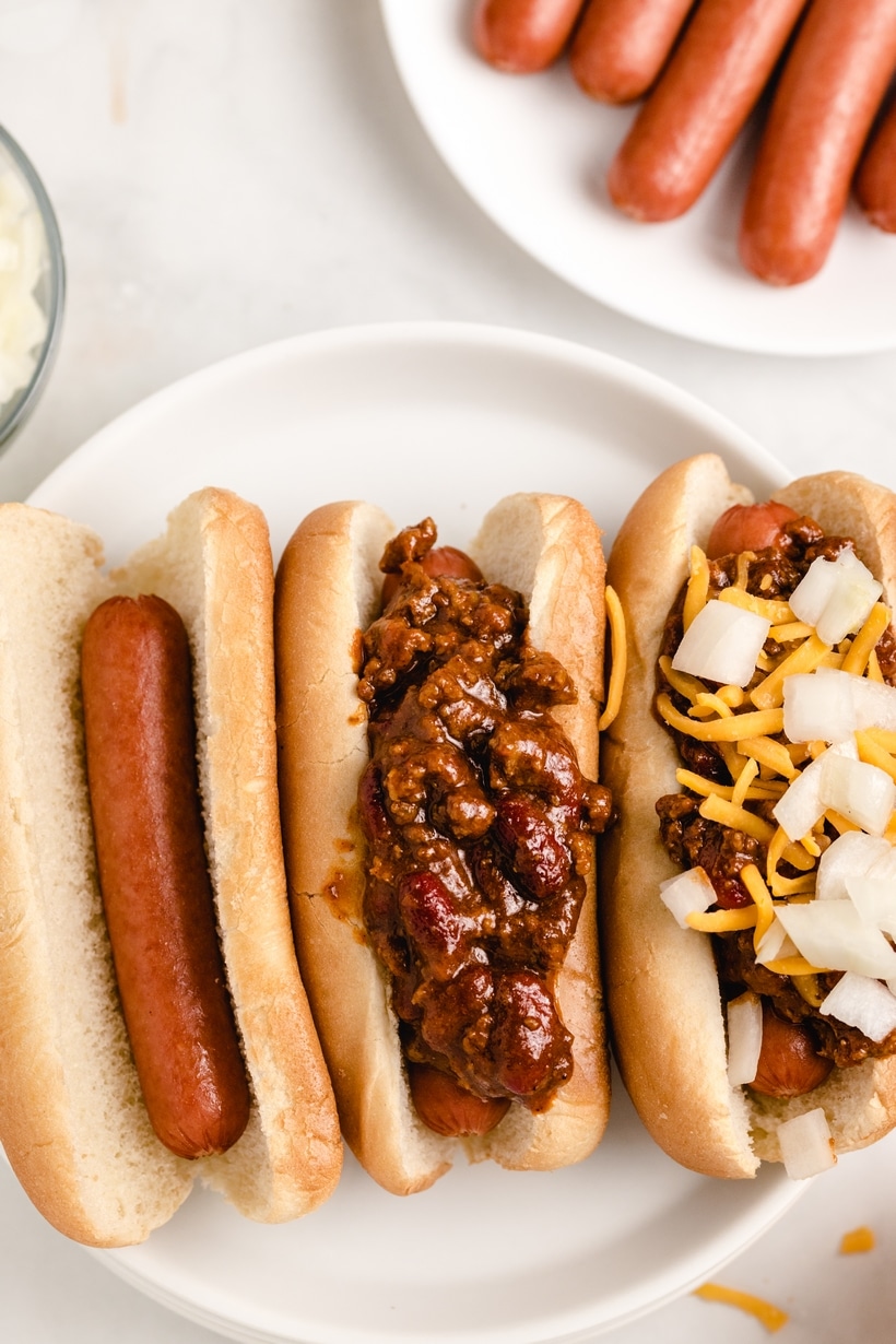 Overhead view of assembling hot dogs with chili and toppings