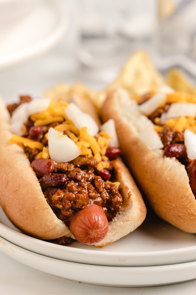 Extreme close-up of a single hot dog topped with chili, cheese, and onions