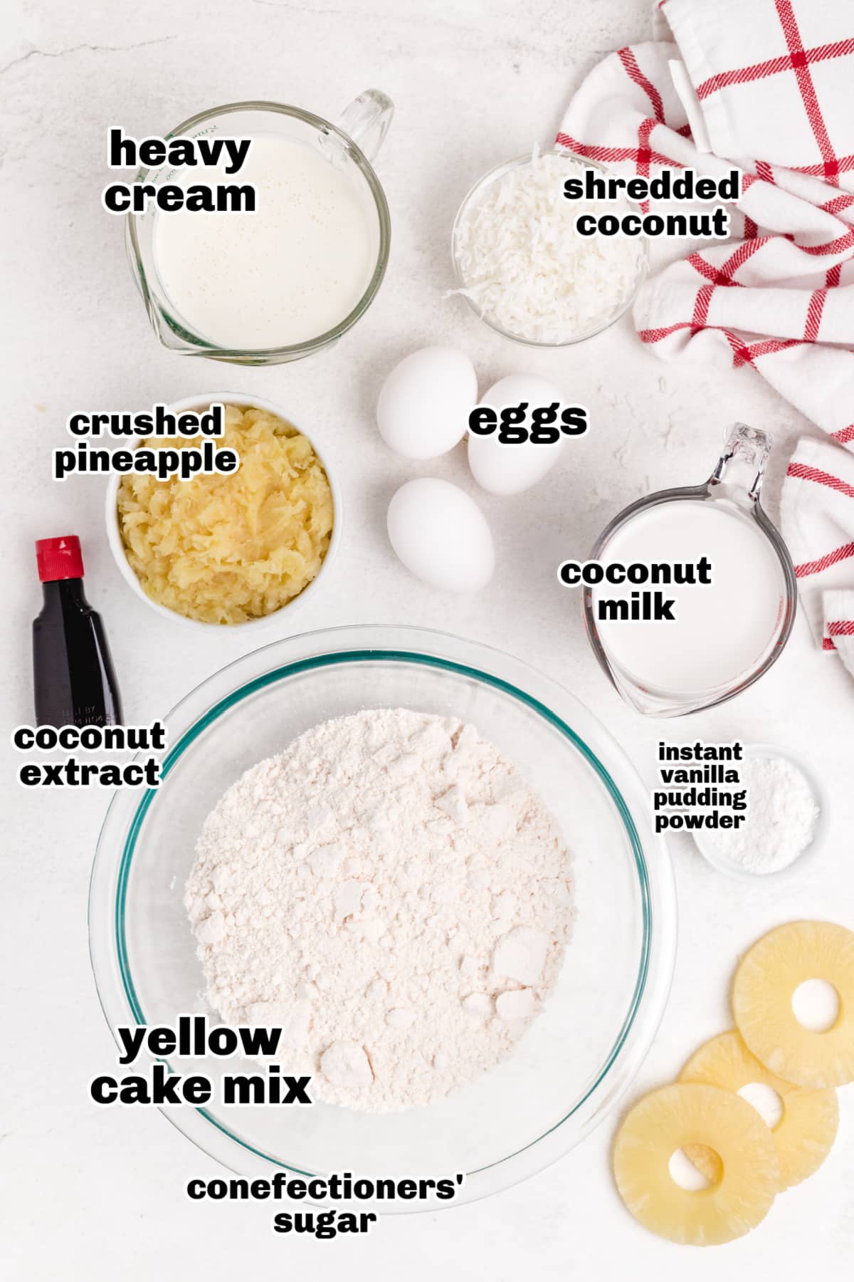 Overhead shot of all the ingredients needed for Piña Colada Cupcakes with Coconut Whipped Cream, including cake mix, coconut milk, pineapple, and whipped cream components.