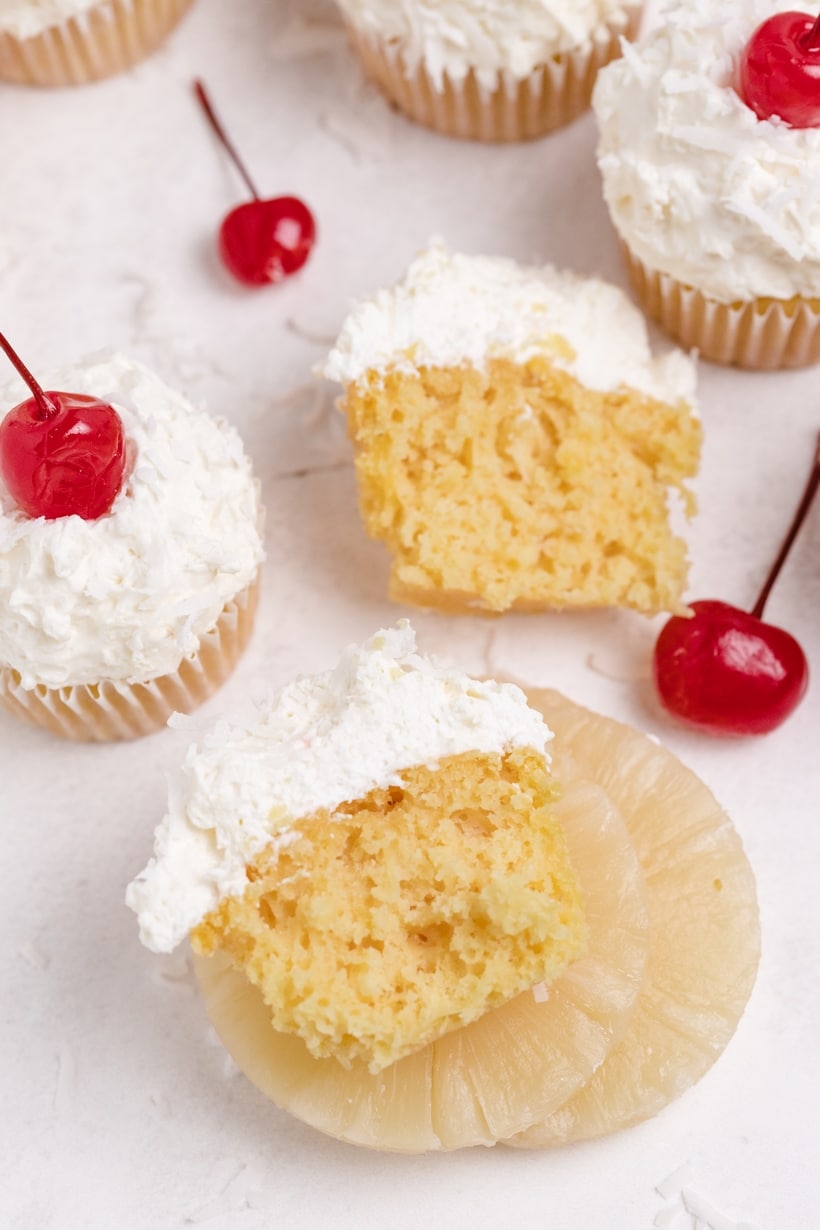  A cupcake cut in half, revealing the soft, moist texture and bits of pineapple inside.