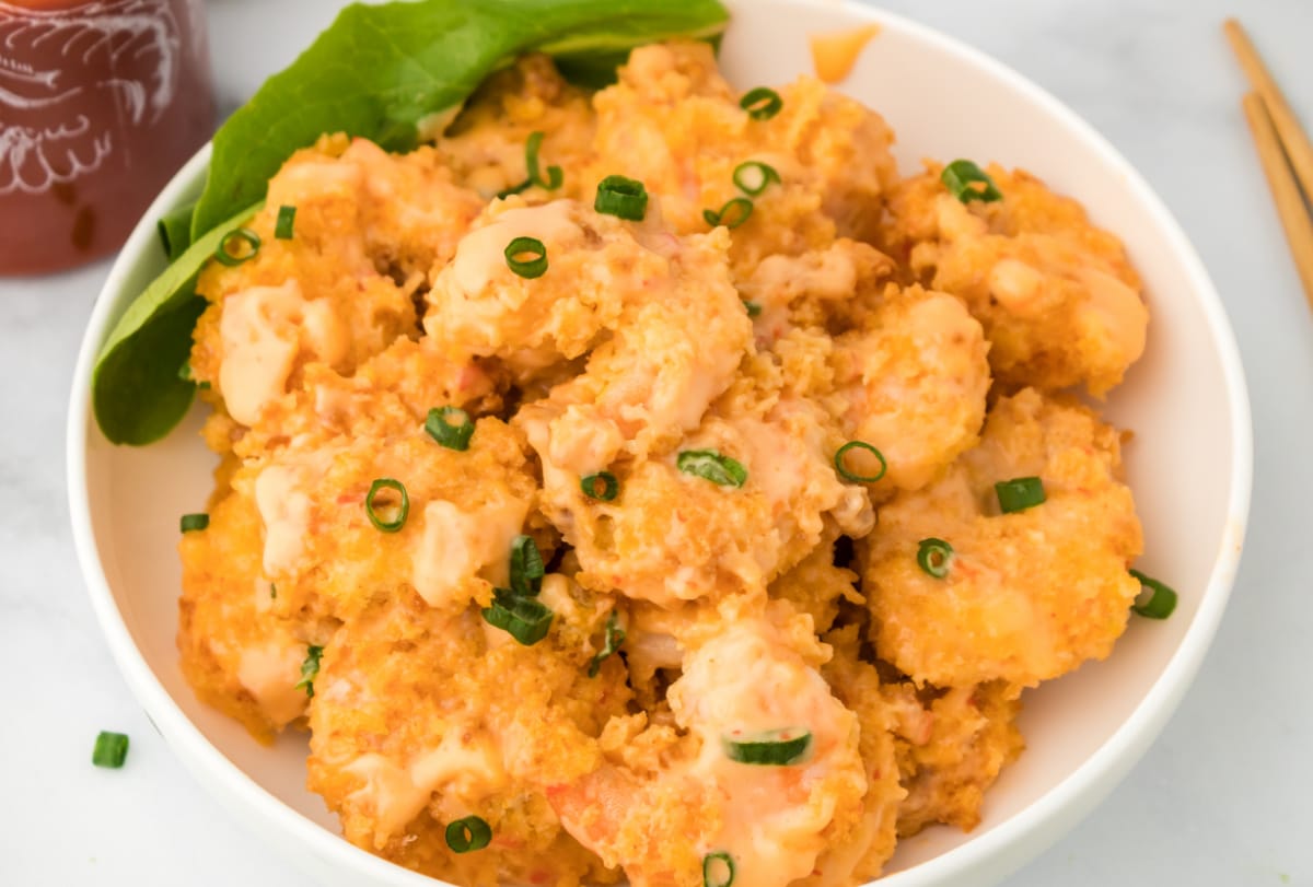 Overhead shot of golden panko-crusted shrimp tossed in bang bang sauce