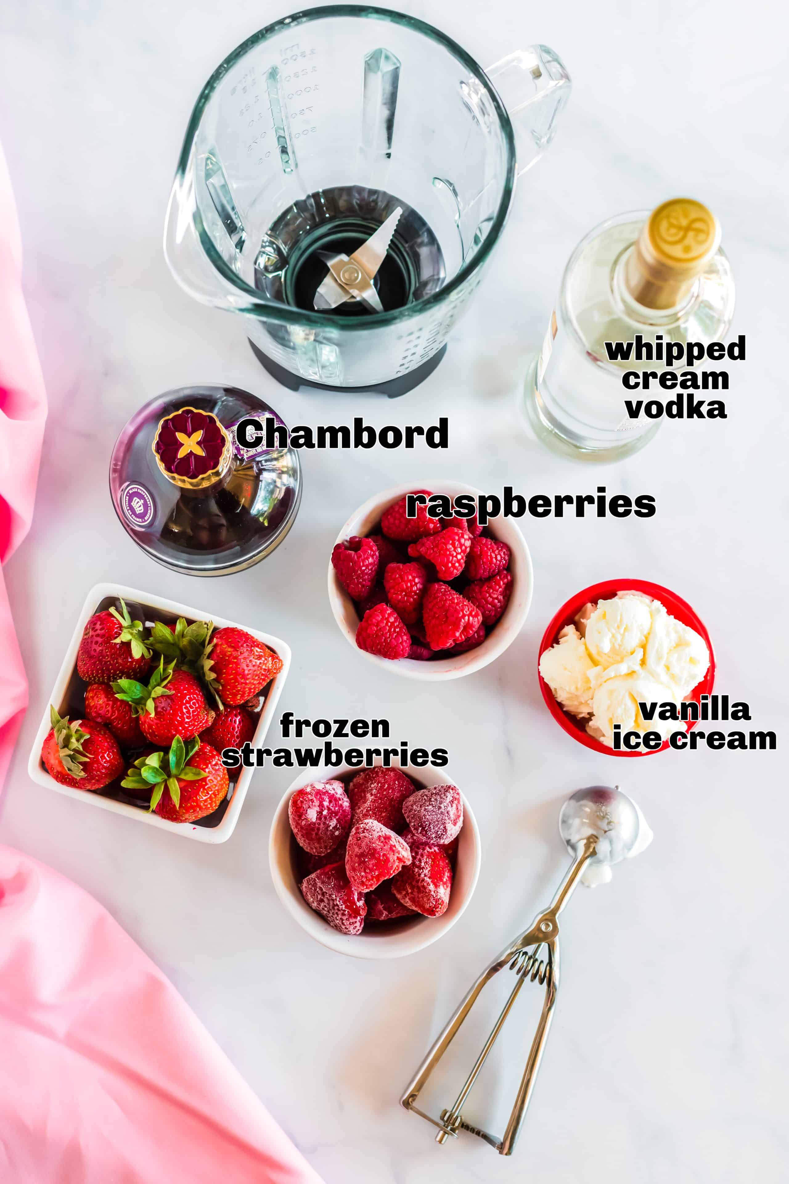 Ingredient shot with Chambord, whipped cream vodka, frozen strawberries, and vanilla ice cream arranged on a countertop.