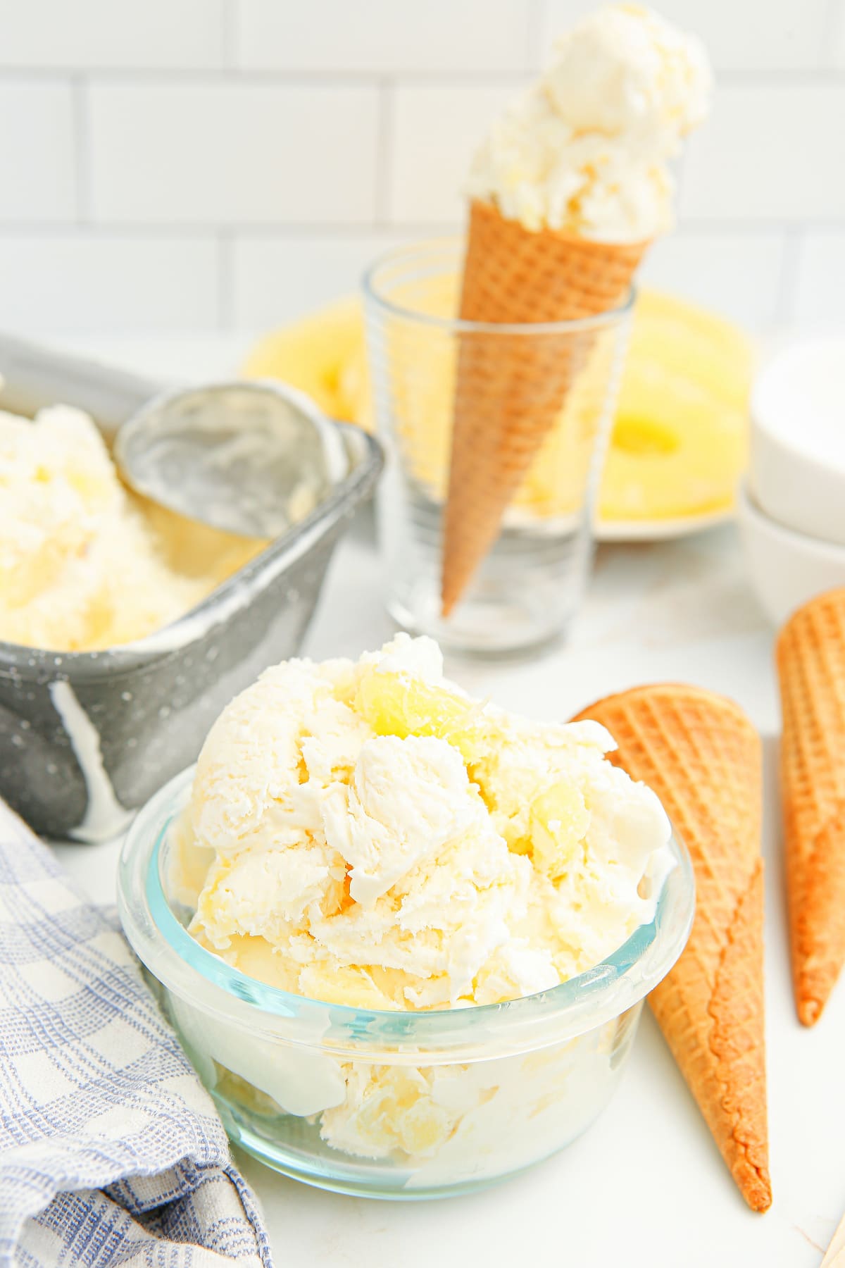 Pineapple ice cream served in a bowl with cones behind it Bowl of no-churn pineapple ice cream with sugar cones in the background