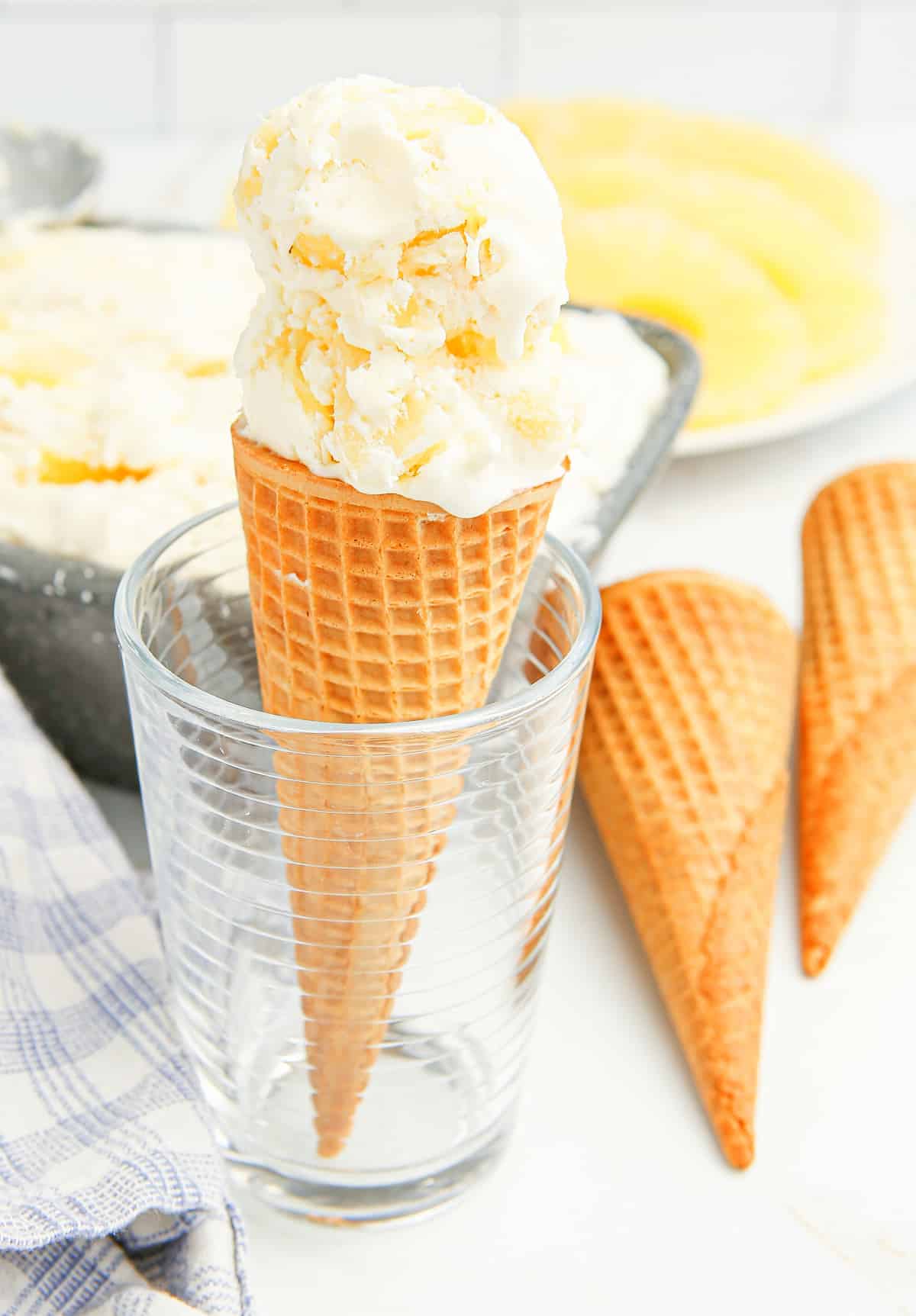No-churn pineapple ice cream cone standing upright in a glass Ice cream cone with two scoops of pineapple ice cream standing in a glass