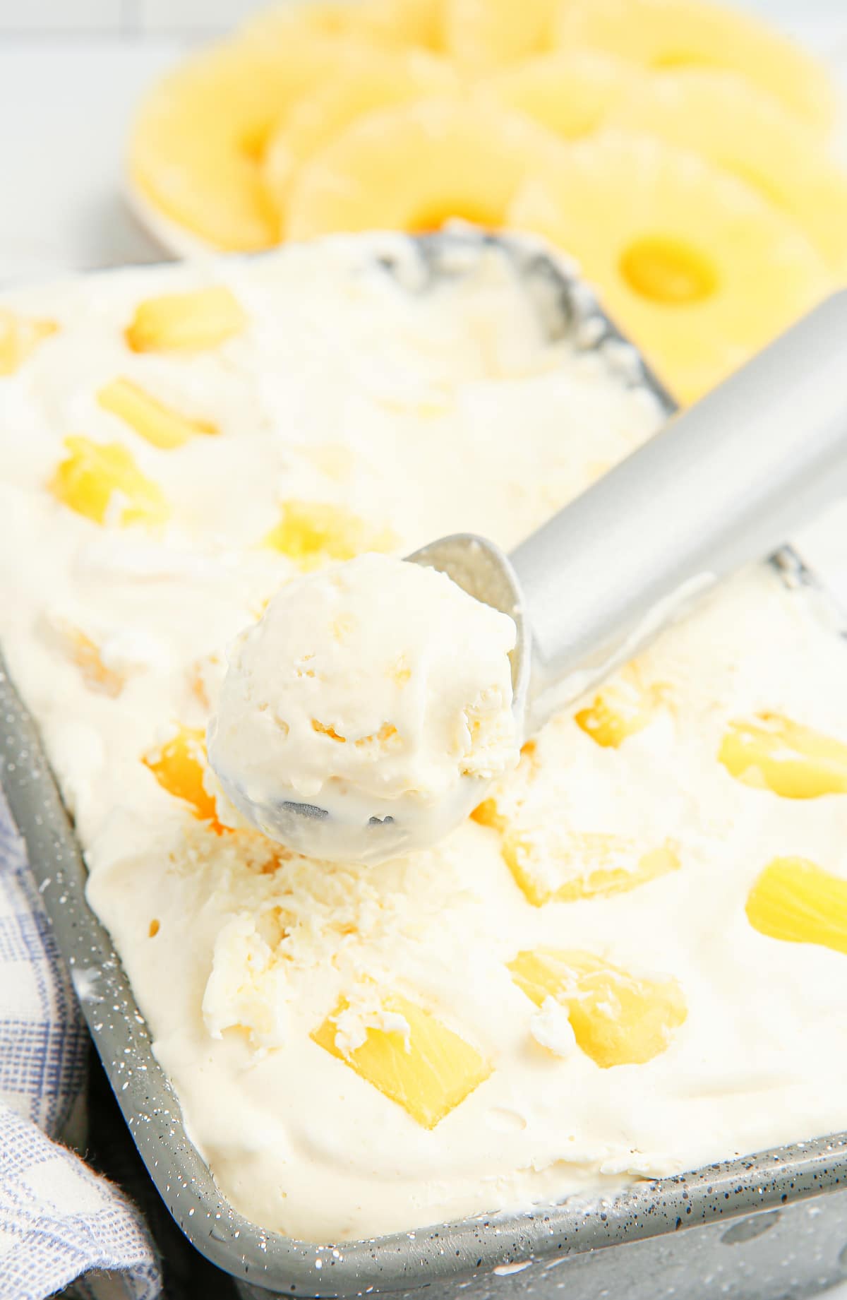 Scooping pineapple ice cream from a frozen loaf pan No-churn pineapple ice cream being scooped from a loaf pan