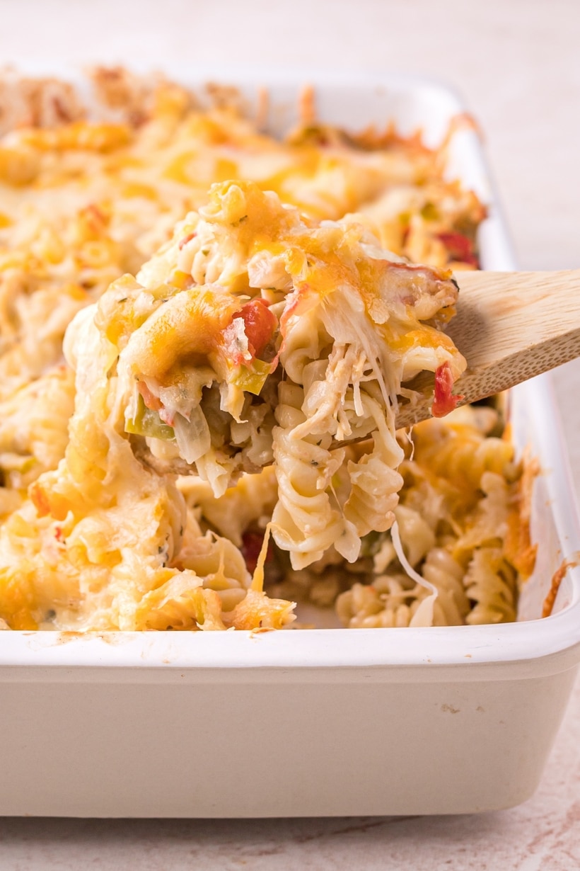 Scoop of Hatch green chile chicken casserole showing melted cheese, rotini, and diced chiles
