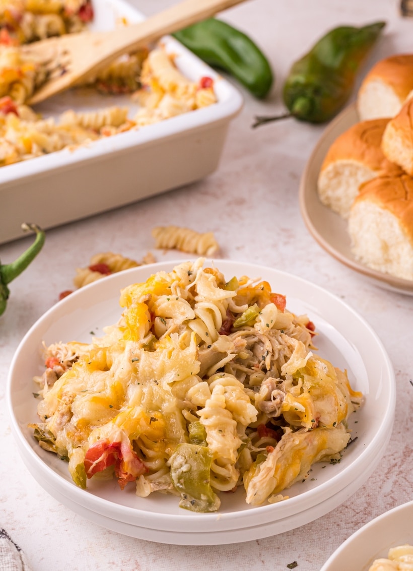 Plate of Hatch chile chicken pasta casserole served with rolls and casserole in background