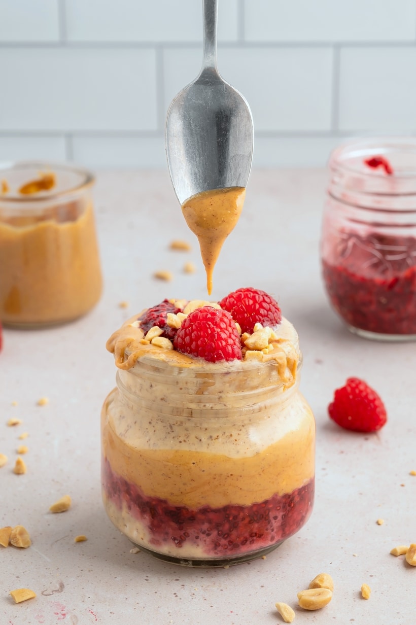 Peanut Butter and Jelly Overnight Oats with a spoon. Spoon scooping out Peanut Butter and Jelly Overnight Oats from a jar.